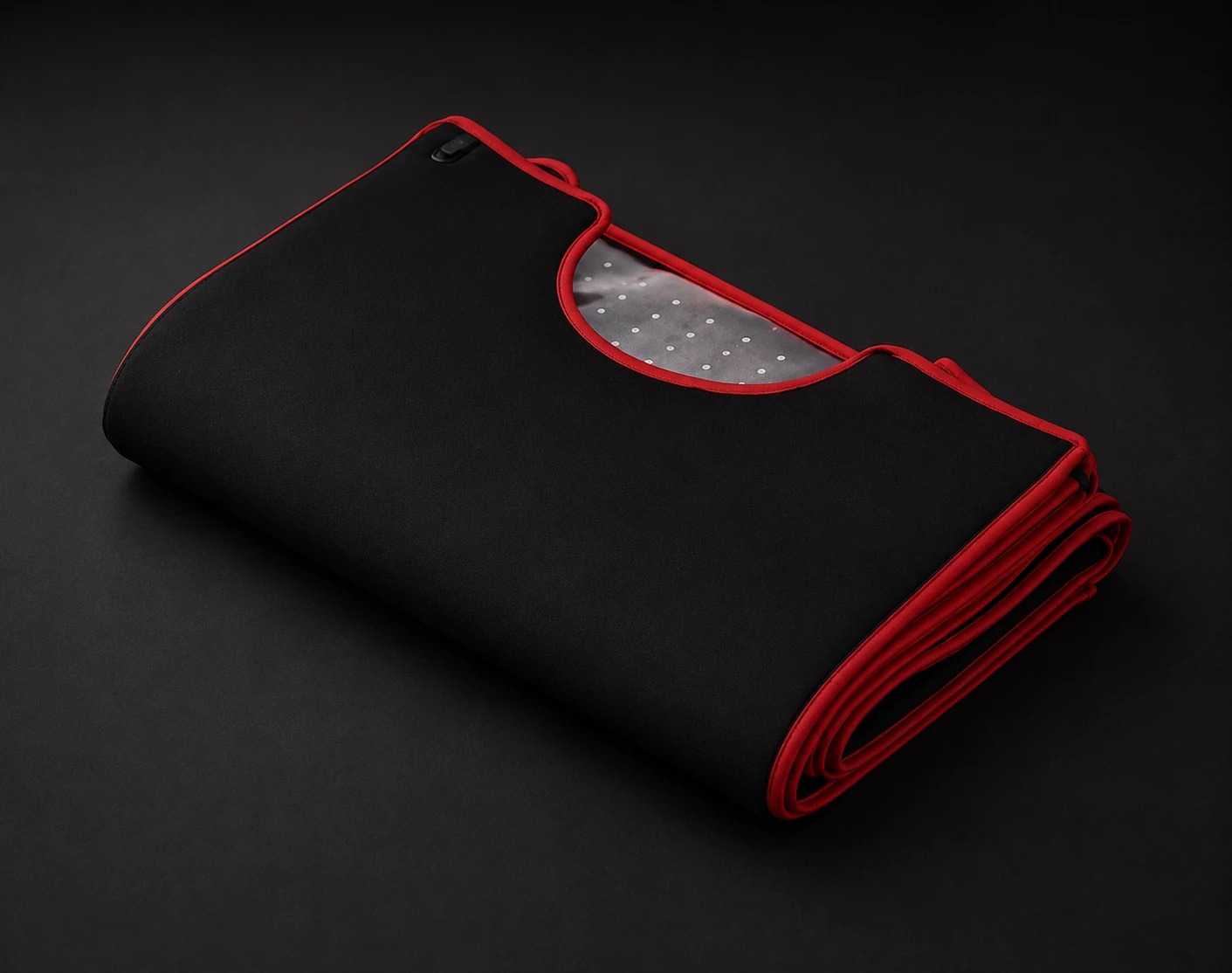 The pod folded flat — matte black with deep-red edge piping